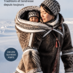 Une maman portant son bébé dans un porte-bébé traditionnel coloré.